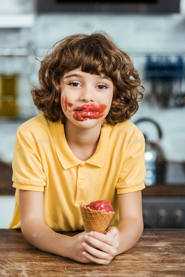 adorable boy with ice cream on face holding delicious ice cream cone