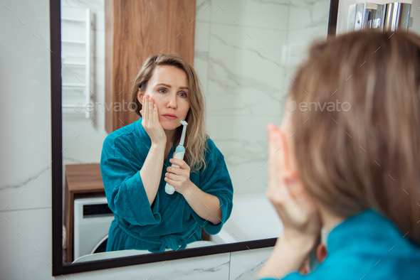 Young woman with frown face expression reflected in mirror