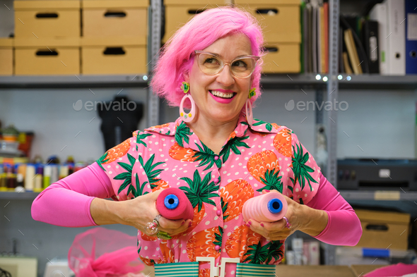 Dressmaker with colorfull clothes making funny faces with sewing thread reels. - Stock Photo - Images