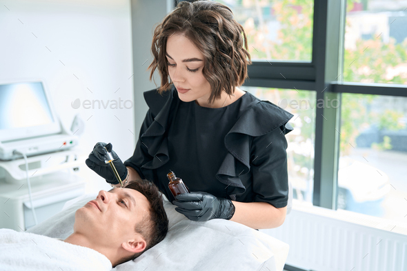 Cosmetologist apply serum for face of redness on man skin - Stock Photo - Images