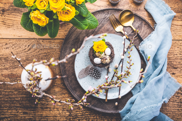 Easter table setting with spring flowers and cutlery on wooden table - Stock Photo - Images