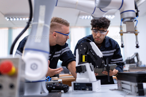 Engineer sitting in robot fabrication room quality checking robot arm ...