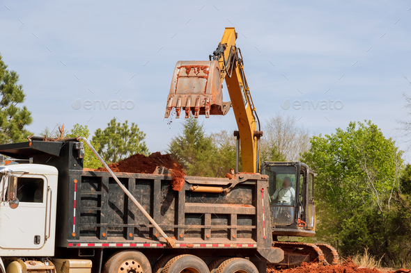 An excavator is loading earth into dump truck on construction site - Stock Photo - Images