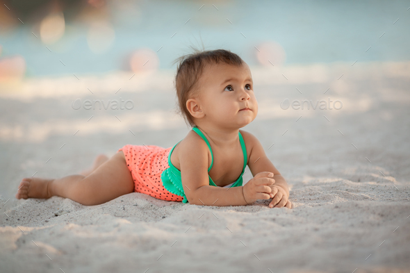 Infant baby girl relaxing on sandy beach at summer vacation - Stock Photo - Images
