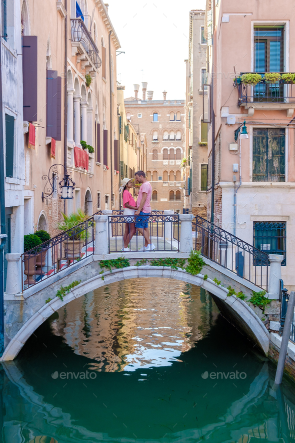 couple men and women on a city trip in Venice Italy sitting at a bridge above the canals of Venice - Stock Photo - Images