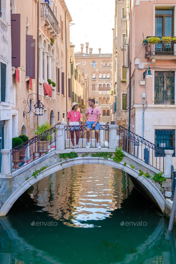 couple men and women on a city trip in Venice Italy sitting above a bridge at the canals of Venice - Stock Photo - Images