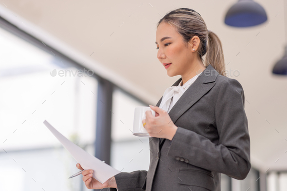 Portrait of a business Asian woman working at office reading and checking searching document tax a