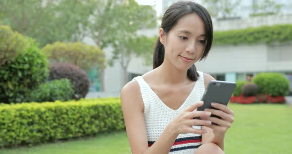 Woman using smart phone at park alt