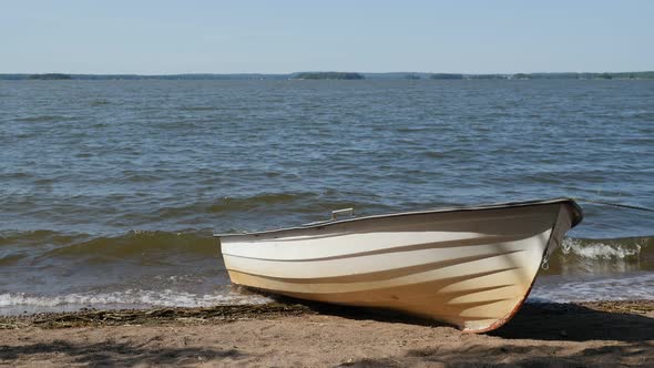 Wooden Fishing Rowboat Beached On Sandy Shore Of Lake