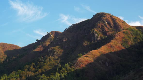 Old large mountains with trees on slopes against blue sky