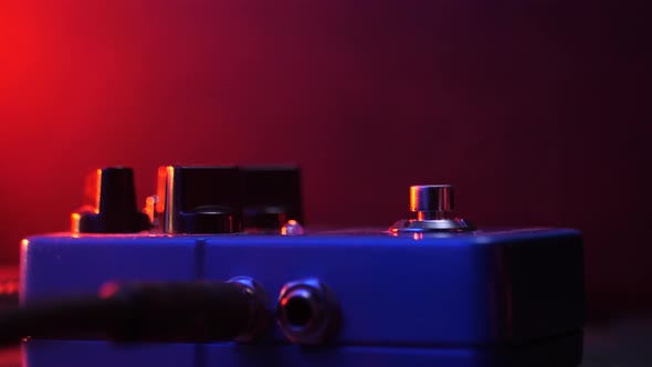 Close up Of Guitar Player Foot in Sneakers Tapping on Metal Pedal. Pink and Blue Neon Light alt