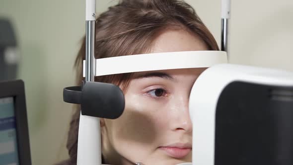 Portrait of Teenager Who Undergoes the Procedure of an Ophthalmoscopy in Clinic alt