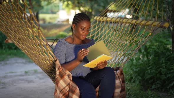 Plussize African American Female Student Turning Workbook Pages in Slow Motion Smiling Sitting in alt