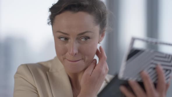 Closeup Portrait of Charming Confident Caucasian Businesswoman Adjusting Makeup Indoors Looking at alt