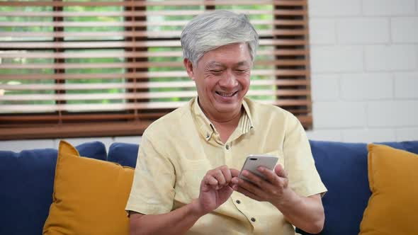 Senior sharing social media communication sitting on a sofa at home in the living room.