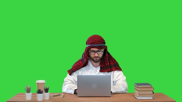 Arabian Businessman Using Laptop at the Table on a Green Screen Chroma Key alt