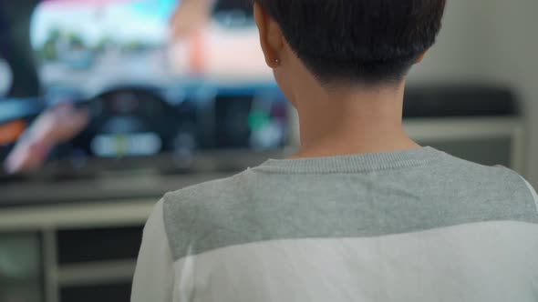 Rear view, young woman playing VDO game on console controlling joystick