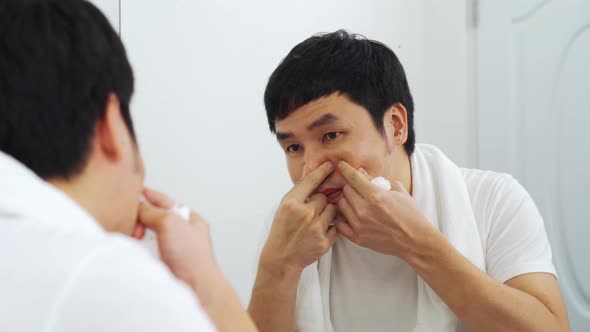man using electric shave to shaving his face in the bathroom mirror