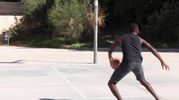 Black man playing basketball on sports ground alt