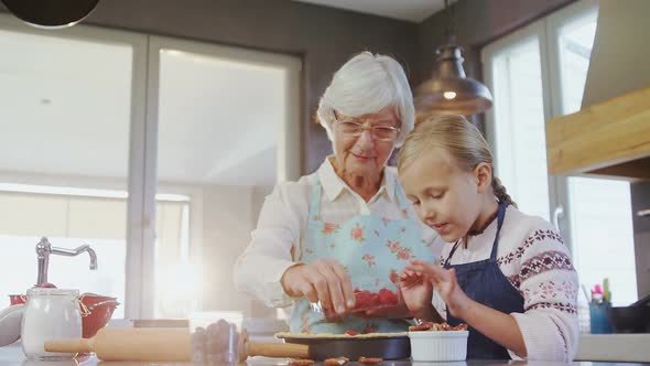 Grandmother and granddaughter plating the pie with strawberries alt