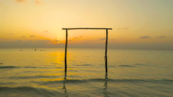 Drone flying through wooden door in ocean during sunset, Maldives alt