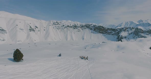 Aerial overflight over a helicopter, a group of skiers and snowboarders in the winter mountains alt