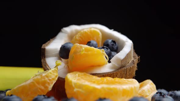 Platter with Mandarin Slices Berries Banana and Half of Coconut