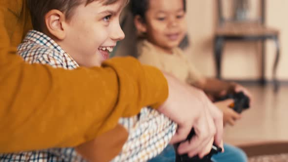 Diverse boys with the help of their fathers playing video games