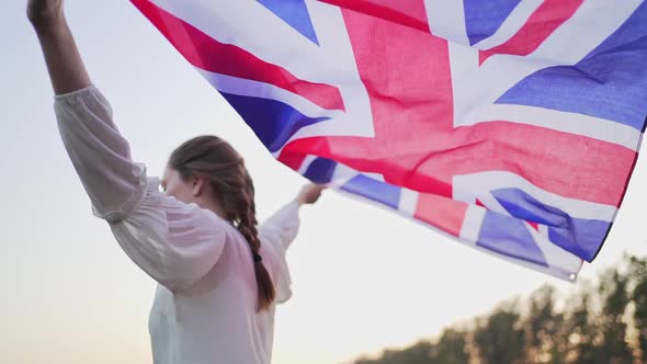 A British Person Carries the National Flag in Her Hands. The Symbol of Great Britain Waving on the