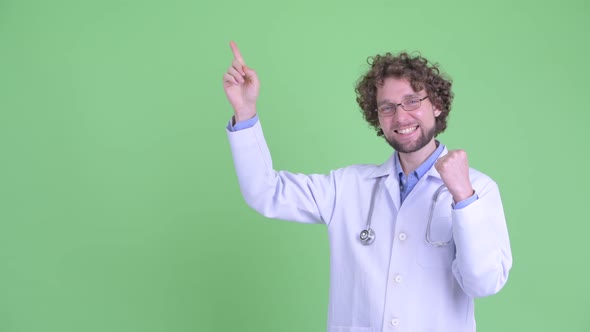Happy Young Bearded Man Doctor Pointing Up and Getting Good News alt