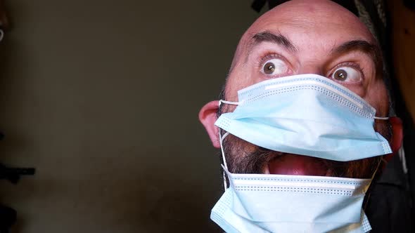Closeup comedy male surprise posing in medical PPE corona virus mask looking at camera room for copy alt