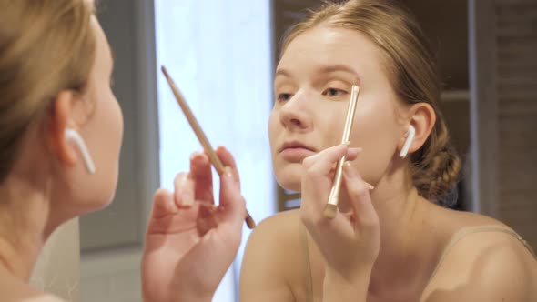 Attractive Woman Putting on Makeup with Brush Adding Blush Bronzer