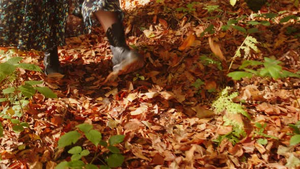 Young Woman Wearing Skirt and Black Boots are Shuffling the Fallen Red and Brown Leaves with Feet
