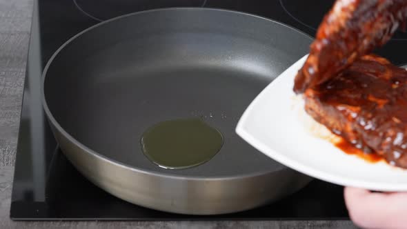 Man Transfers Meat to a Pan with Oil From White Plate for Cooking alt