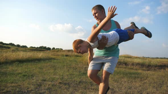 Cheerful Dad Holding and Rotates His Little Child in Hands alt