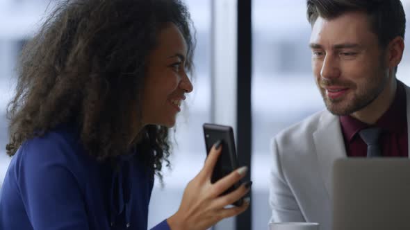 Happy Businesswoman Showing Phone Sharing Good News with Man Colleague in Office alt