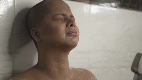 Sick and weak bald nude Asian girl is bathing with hand shower in bathroom is very upset and crying alt