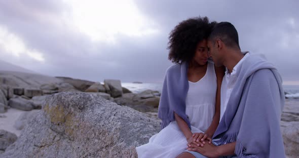 Couple wrapped in blanket on beach 4k