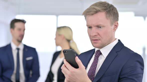Portrait of Disappointed Businessman Reacting To Failure on Smartphone alt