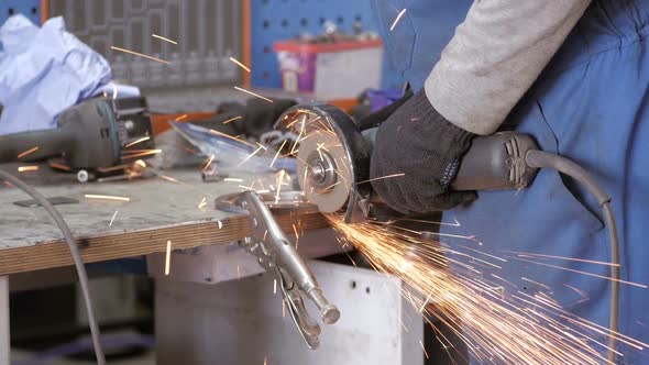 A Worker Works With Grinder. Hands Of Workman Cutting Metal Detail With Grinder