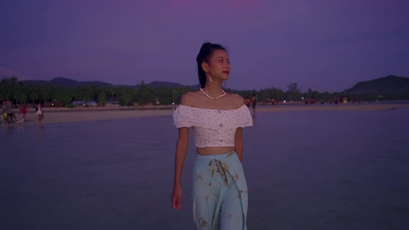 Young Asian Woman Walking Alone in the Sea at Sunset Thailand alt