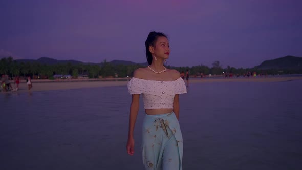 Young Asian Woman Walking Alone in the Sea at Sunset Thailand