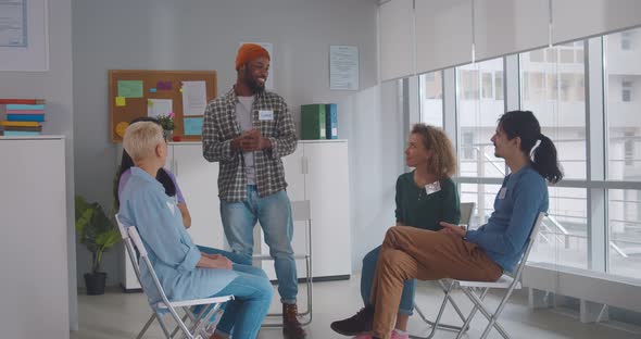 Excited African American Man Standing in Circle at Team Therapy Session Talking Sharing Thoughts alt