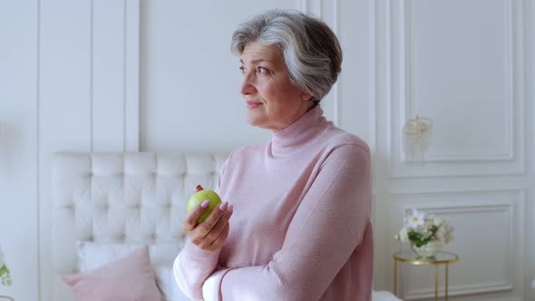 Smiling Elderly Woman Holding a Green Apple in Her Hands, Healthy Diet Concept alt