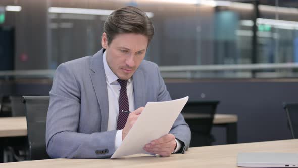 Middle Aged Businessman with Documents Reacting to Loss  alt