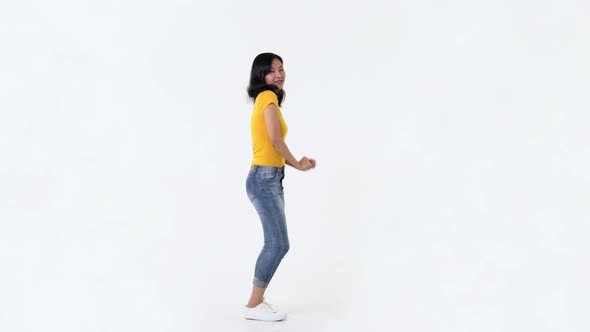 Happy young Asian woman in yellow t-shirt having fun smiling and dancing