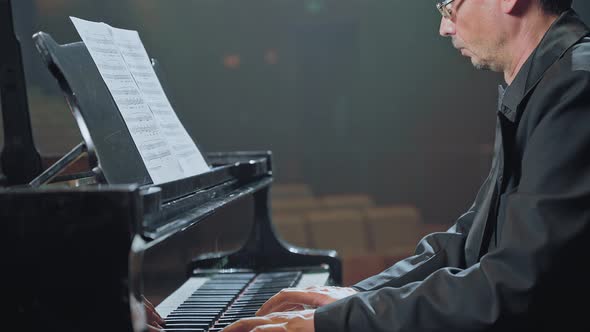 Pianist in Dark Suit Playing on a Grand Piano on Big Stage