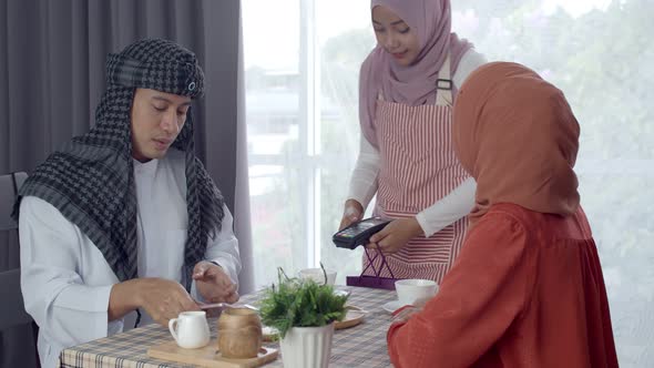 Young muslim man use smartphone contactless payment in coffee shop