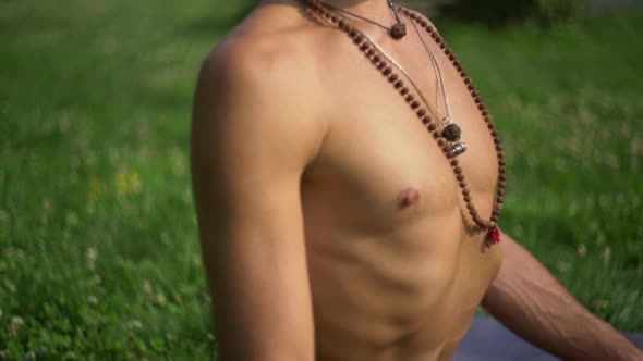 Yogi Meditating in Lotus Posay on a Background of Green Grass Day alt