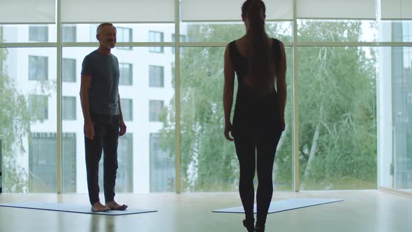 Wide Shot of Professional Yoga Master Welcoming Client in Gym, Mid-adult Caucasian Man and Young alt
